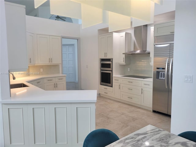 kitchen featuring sink, appliances with stainless steel finishes, backsplash, white cabinets, and wall chimney range hood