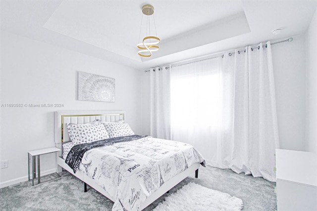 bedroom with light colored carpet and a tray ceiling