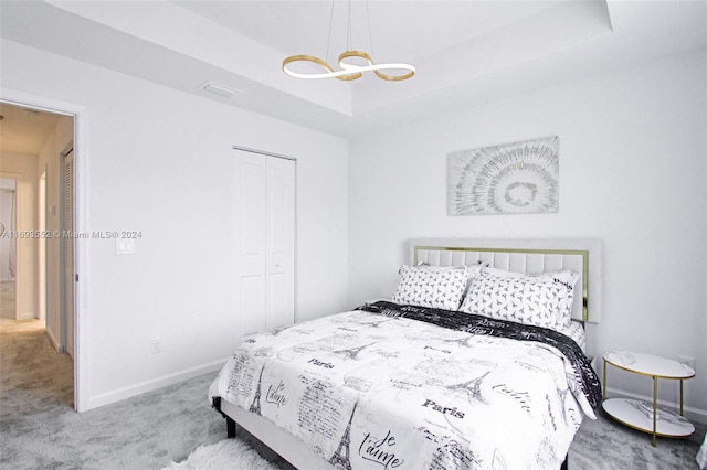 carpeted bedroom featuring a tray ceiling and a closet