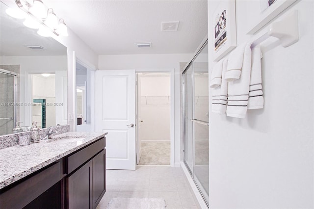 bathroom featuring tile patterned floors, a textured ceiling, vanity, and an enclosed shower