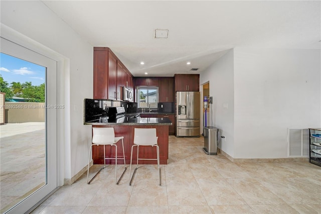 kitchen featuring visible vents, appliances with stainless steel finishes, dark stone countertops, a peninsula, and recessed lighting