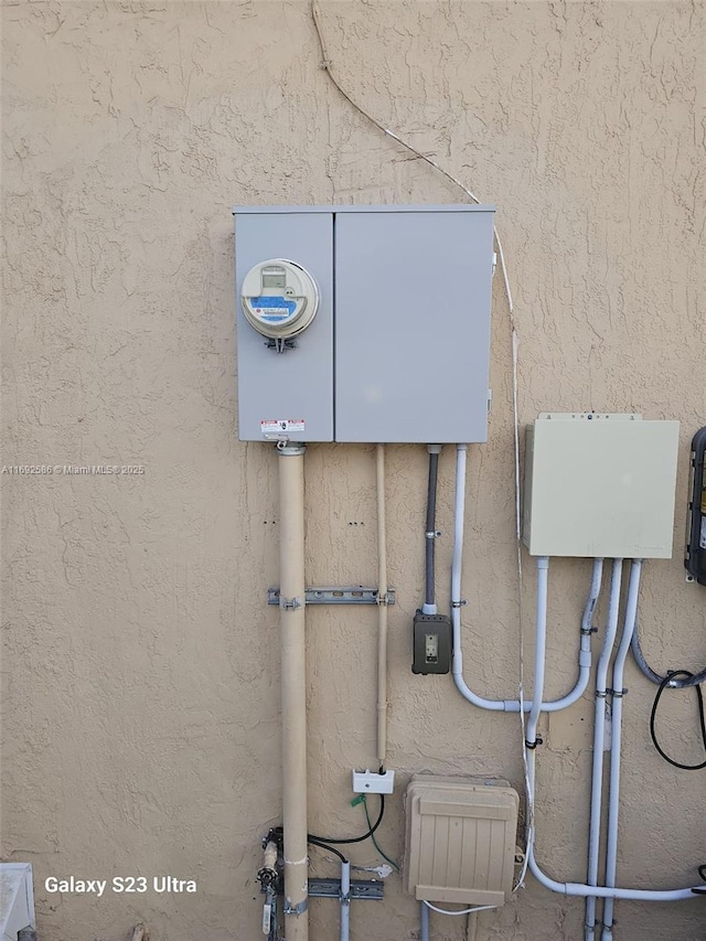 details featuring electric meter and stucco siding