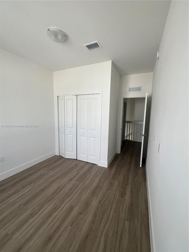 unfurnished bedroom featuring a closet and dark hardwood / wood-style flooring