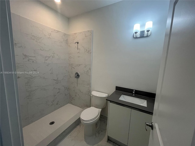 bathroom featuring vanity, a tile shower, and toilet