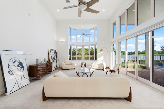 living room with carpet floors, ceiling fan, a water view, and a high ceiling
