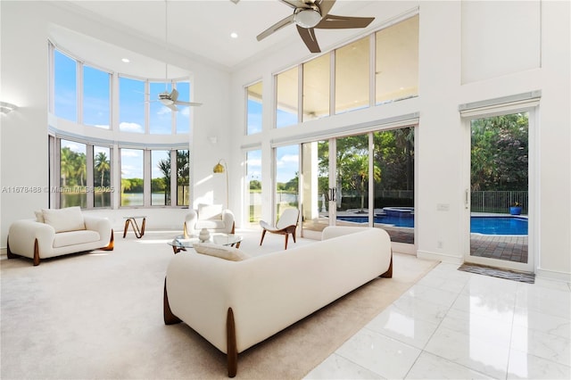 living room with a ceiling fan, a high ceiling, and a healthy amount of sunlight