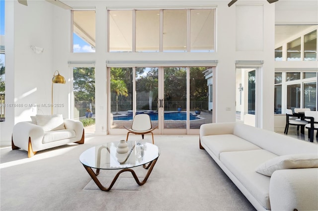 living room featuring carpet, a high ceiling, and a healthy amount of sunlight