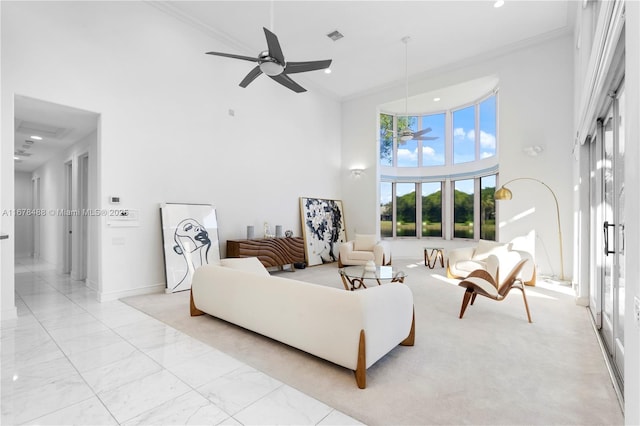 living area featuring a ceiling fan, ornamental molding, baseboards, and a towering ceiling