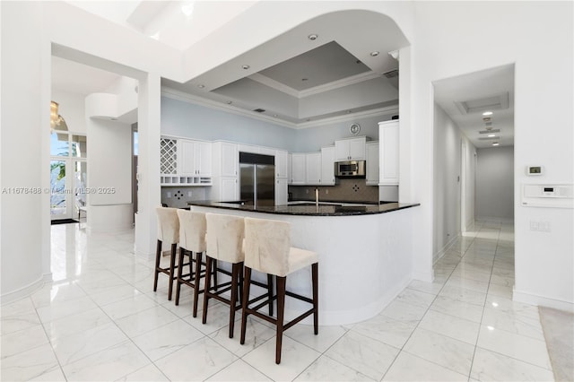 kitchen featuring stainless steel appliances, ornamental molding, marble finish floor, and a towering ceiling