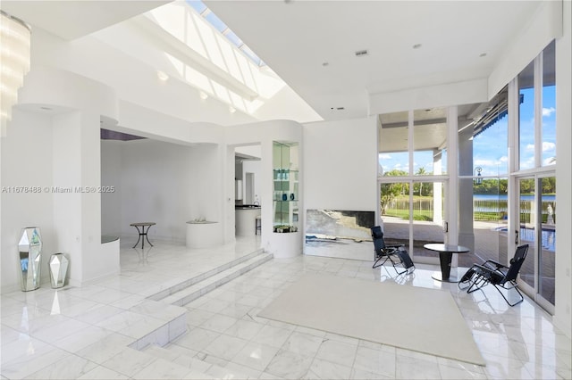 bathroom featuring a freestanding tub, a water view, marble finish floor, and a towering ceiling