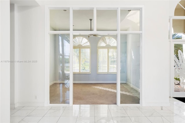 interior space with a ceiling fan, baseboards, arched walkways, and marble finish floor