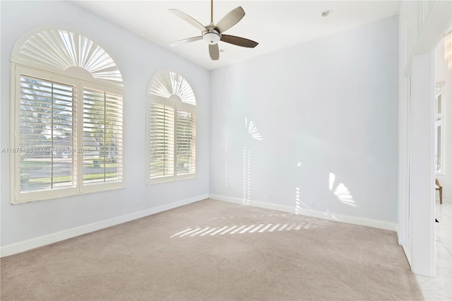 unfurnished room with baseboards, light carpet, and a ceiling fan