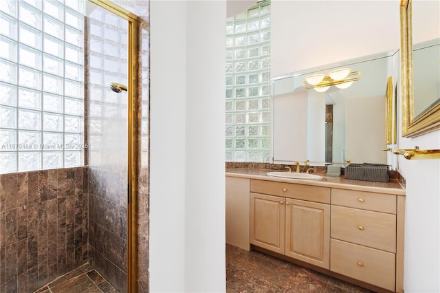 full bath with a healthy amount of sunlight, vanity, and tiled shower