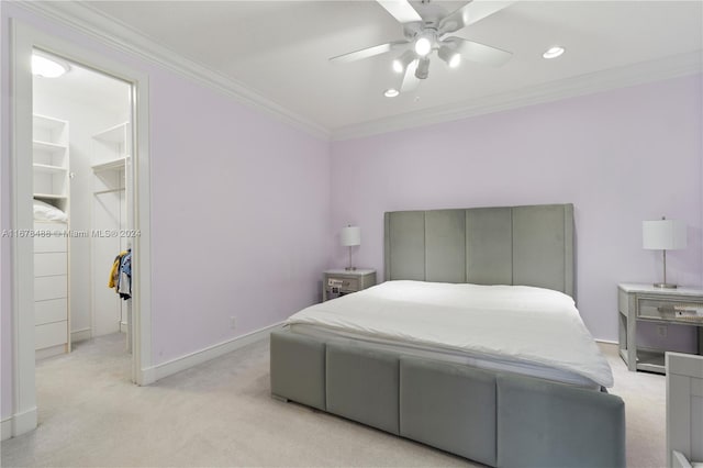 bedroom with light carpet, ornamental molding, ceiling fan, a spacious closet, and a closet