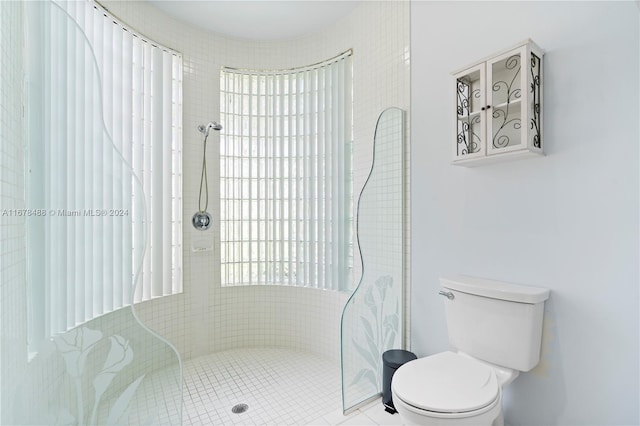 bathroom with a tile shower, tile patterned flooring, and toilet