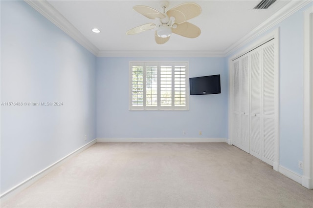 unfurnished bedroom with ceiling fan, a closet, light colored carpet, and crown molding