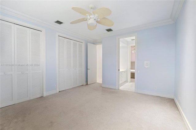 unfurnished bedroom with ensuite bath, ceiling fan, crown molding, and multiple closets