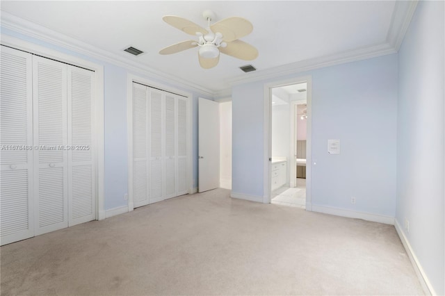 unfurnished bedroom with crown molding, light carpet, two closets, and visible vents