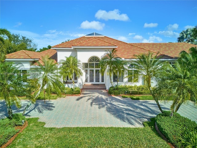 mediterranean / spanish-style house with french doors, stucco siding, and a tile roof
