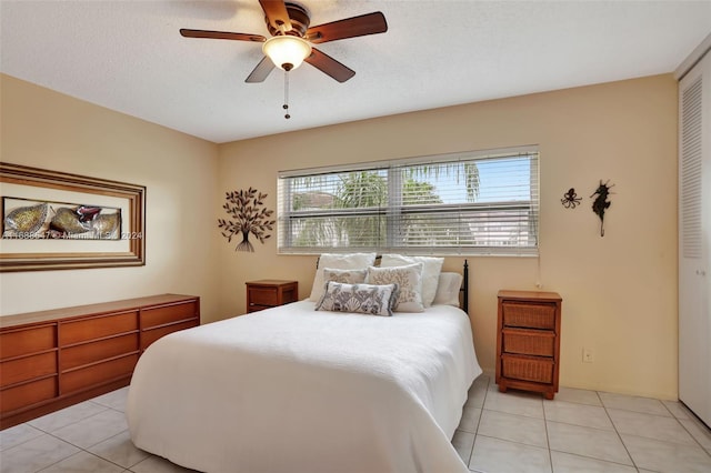 bedroom featuring light tile patterned floors, a textured ceiling, a closet, and ceiling fan