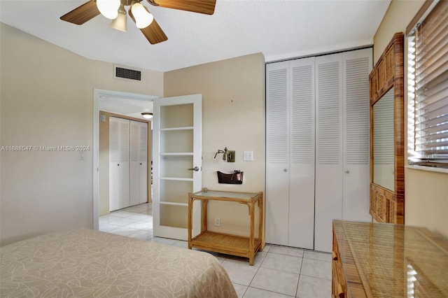 bedroom featuring ceiling fan, light tile patterned flooring, and a textured ceiling