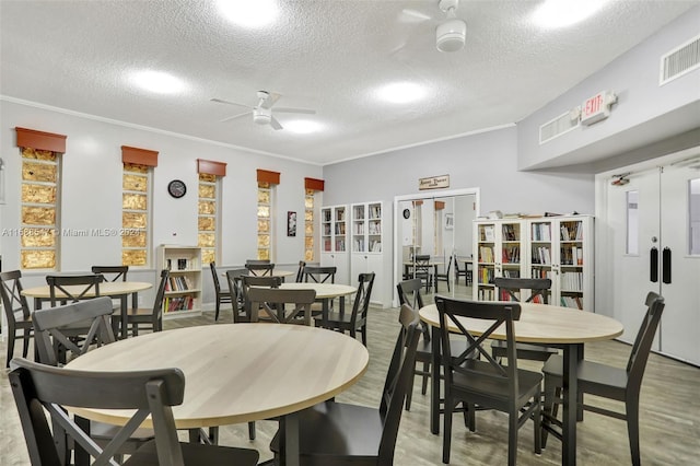 dining room featuring light hardwood / wood-style flooring, a textured ceiling, and ornamental molding