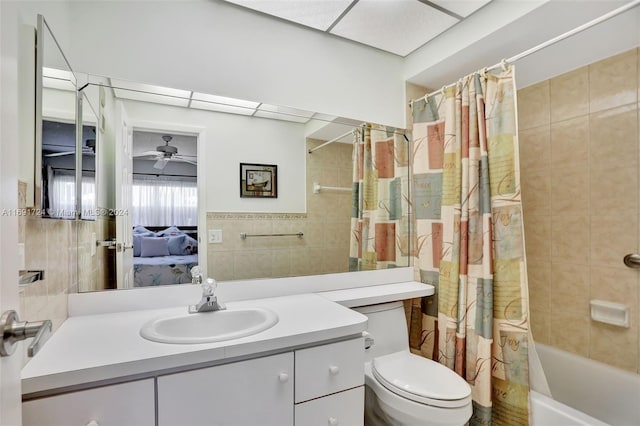 full bathroom with shower / tub combo, vanity, ceiling fan, tile walls, and toilet