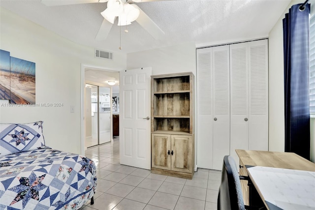 tiled bedroom with a closet, ceiling fan, and a textured ceiling