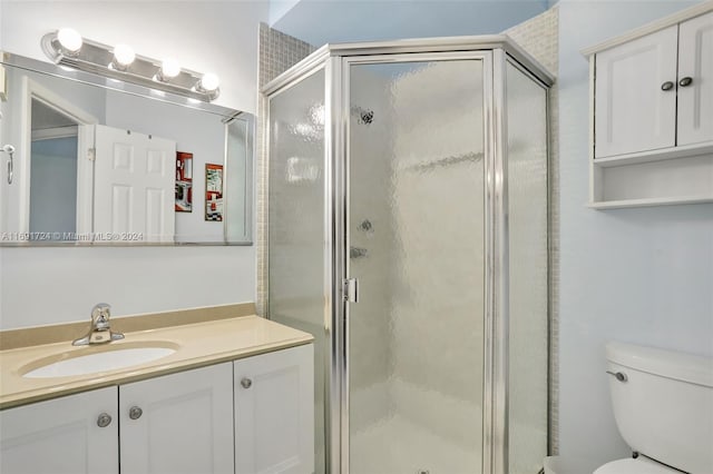 bathroom with vanity, toilet, and a shower with shower door