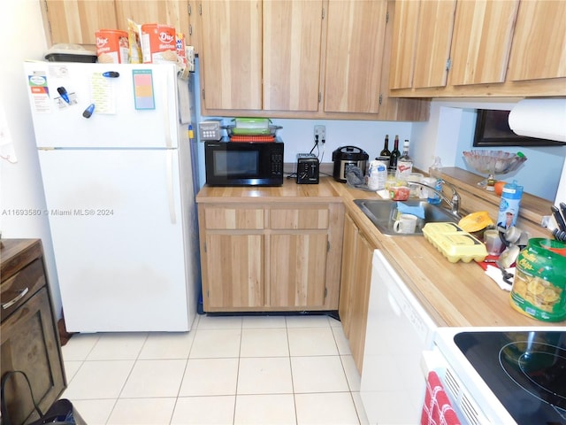 kitchen featuring light tile patterned floors, white appliances, and sink