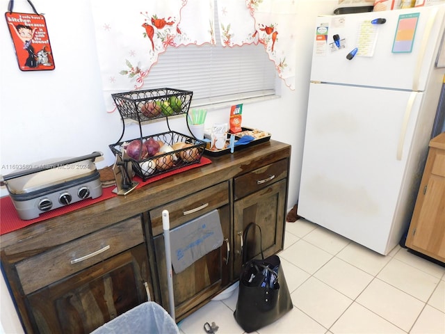 kitchen featuring dark brown cabinetry, white fridge, and light tile patterned floors