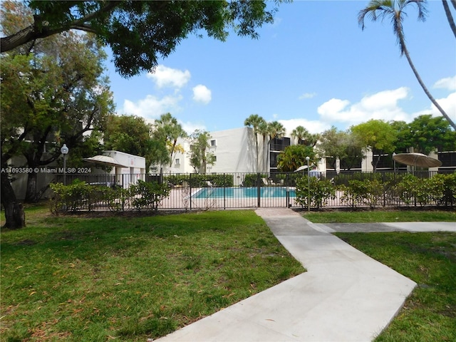 view of property's community with a pool and a yard