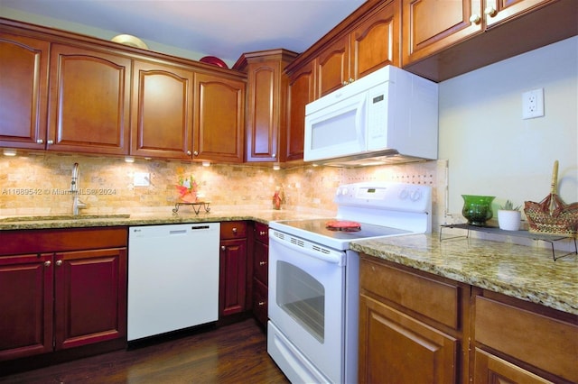 kitchen with light stone countertops, sink, dark wood-type flooring, backsplash, and white appliances