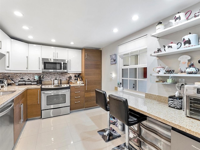 kitchen with white cabinets, stainless steel appliances, and light stone countertops