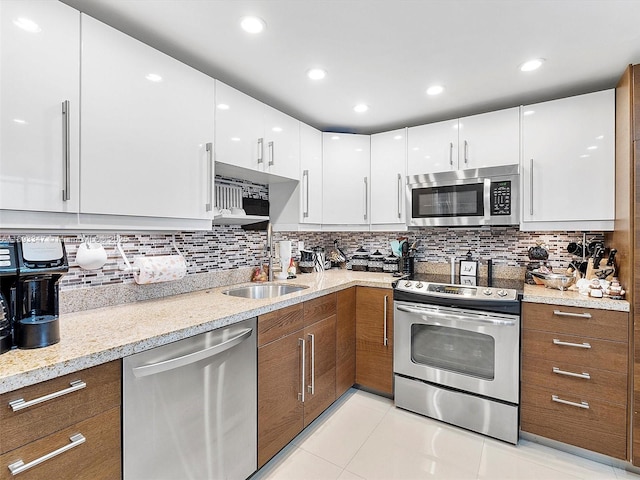 kitchen featuring white cabinetry, stainless steel appliances, light stone counters, and sink