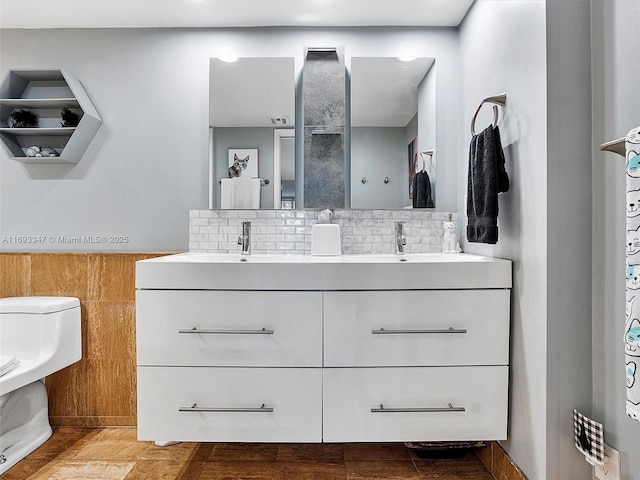 bathroom with vanity, toilet, and backsplash