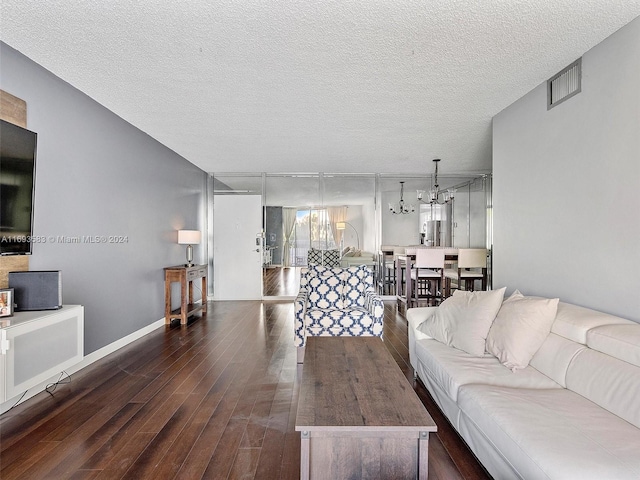 living room featuring a textured ceiling, dark hardwood / wood-style floors, and a notable chandelier