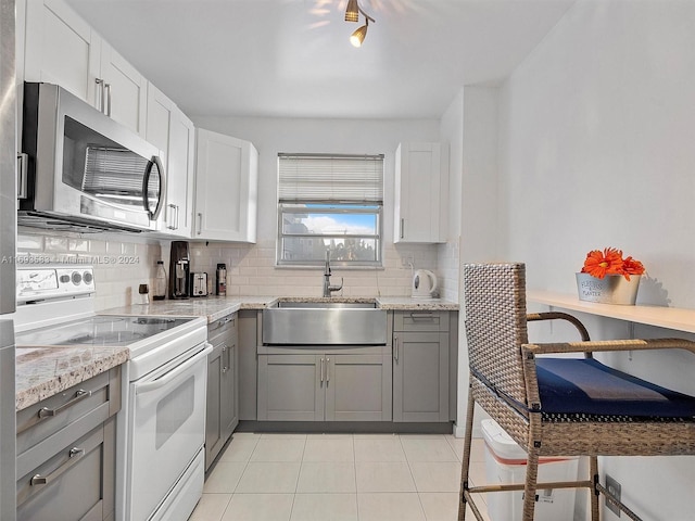 kitchen featuring light tile patterned floors, white cabinetry, white range with electric cooktop, and sink