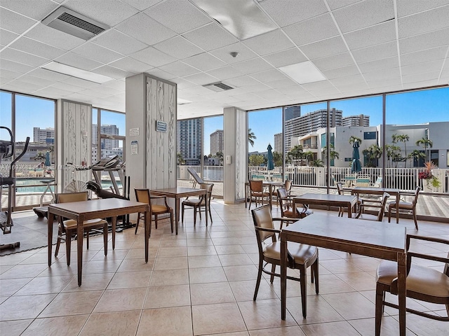 dining space featuring light tile patterned floors, a paneled ceiling, and expansive windows