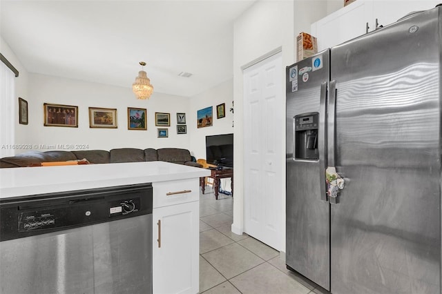 kitchen with light tile patterned flooring, white cabinetry, stainless steel appliances, and hanging light fixtures