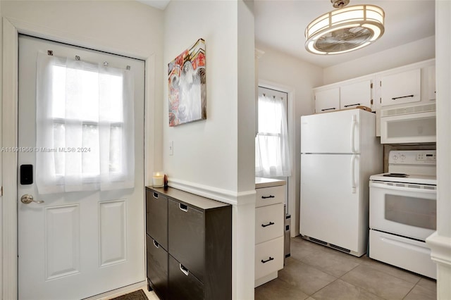 kitchen with white appliances, white cabinetry, light tile patterned flooring, and plenty of natural light