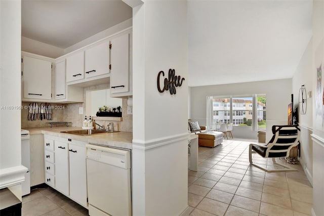 kitchen featuring dishwasher, sink, light tile patterned flooring, backsplash, and white cabinets