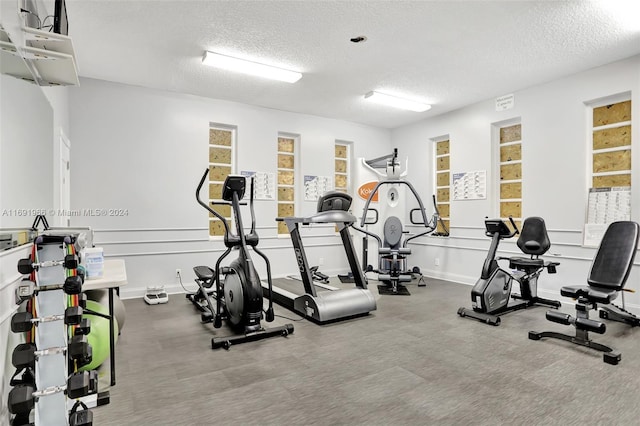 gym with plenty of natural light, carpet, and a textured ceiling