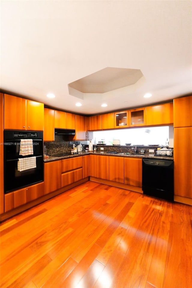 kitchen with black appliances, light hardwood / wood-style floors, and a tray ceiling