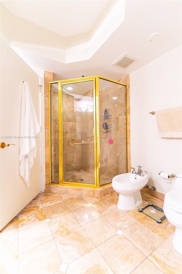 bathroom featuring tile patterned floors, toilet, a shower with shower door, and a bidet