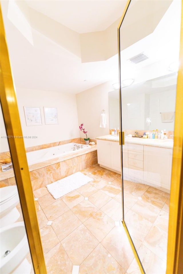 bathroom featuring tile patterned flooring, vanity, toilet, and tiled bath