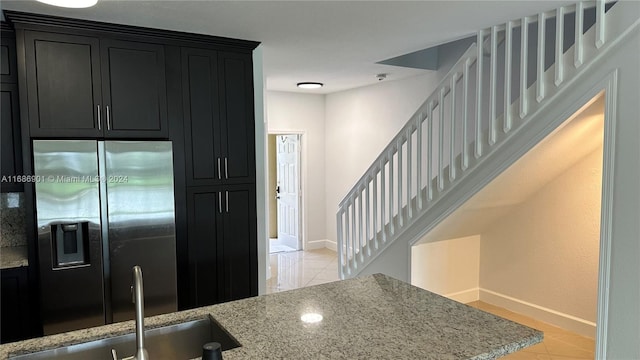 kitchen featuring stainless steel fridge, sink, light tile patterned floors, and light stone counters