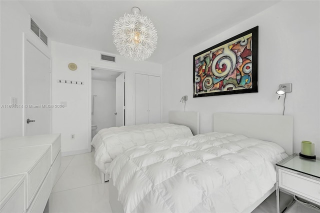 tiled bedroom with ensuite bath and an inviting chandelier