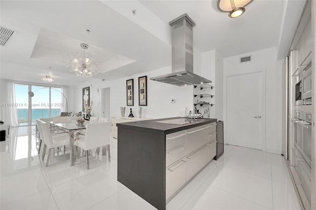 18201 Collins Ave Unit 1002, Sunny Isles Beach, FL 33160 - kitchen with island exhaust hood, modern cabinets, electric cooktop, a chandelier, and dark countertops