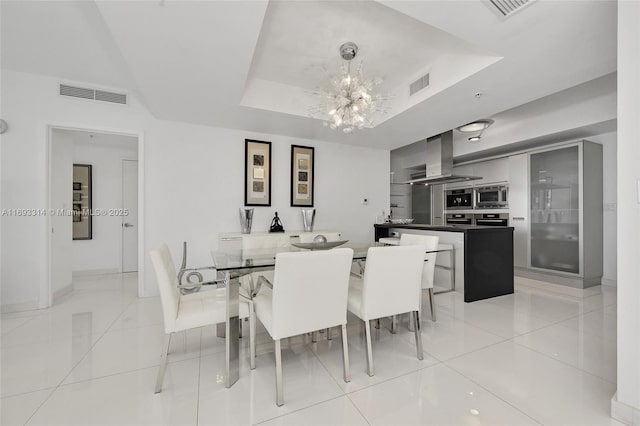 dining space featuring a chandelier, light tile patterned floors, and a tray ceiling